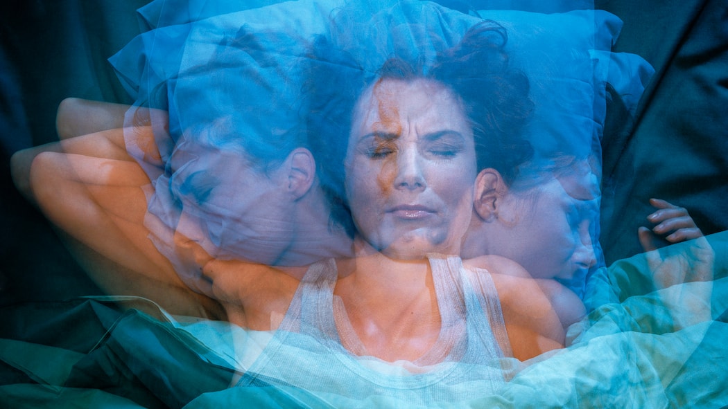 Was tun, wenn negative Gedanken den Schlaf rauben? Eine Frau wälzt sich nachts im Bett hin und her.