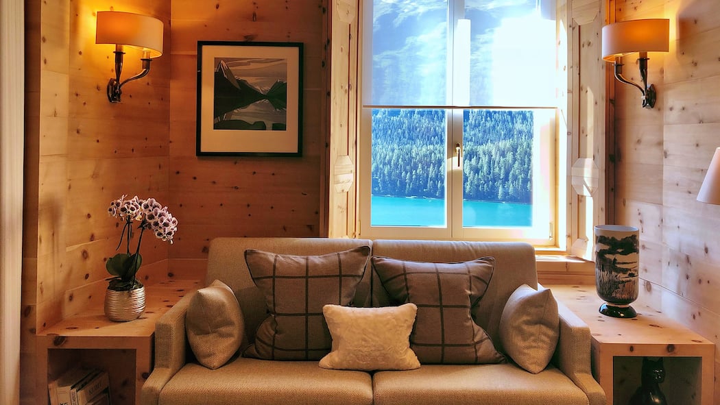 Der teure Traum vom Ferienhaus Eine schön eingerichtete Stube einer Ferienwohnung mit Blick auf einen See und Wälder.