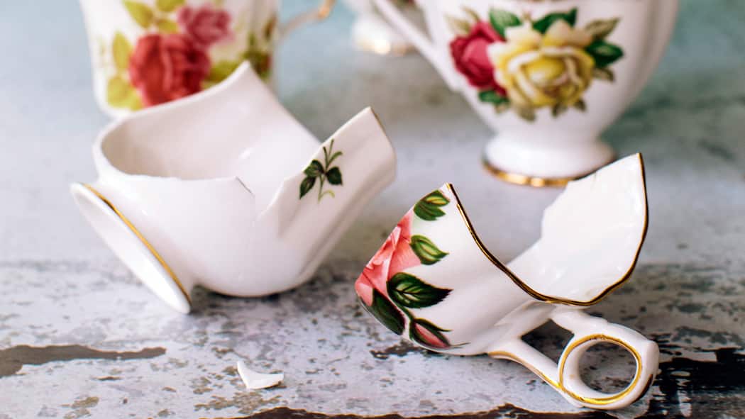 Hilfe für zerstrittene Erben Kaffeetassen mit einem floralen Muster liegen zerbrochen auf einem Tisch.