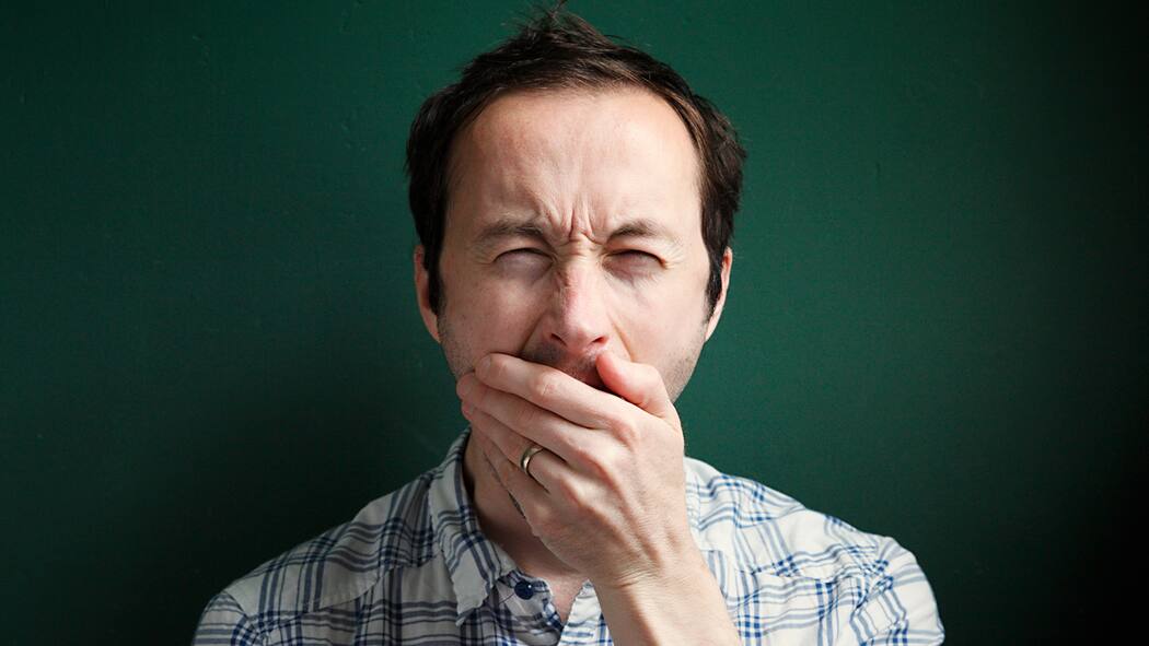 Wie krank macht chronische Übermüdung? Ein übermüdeter Mann gähnt.