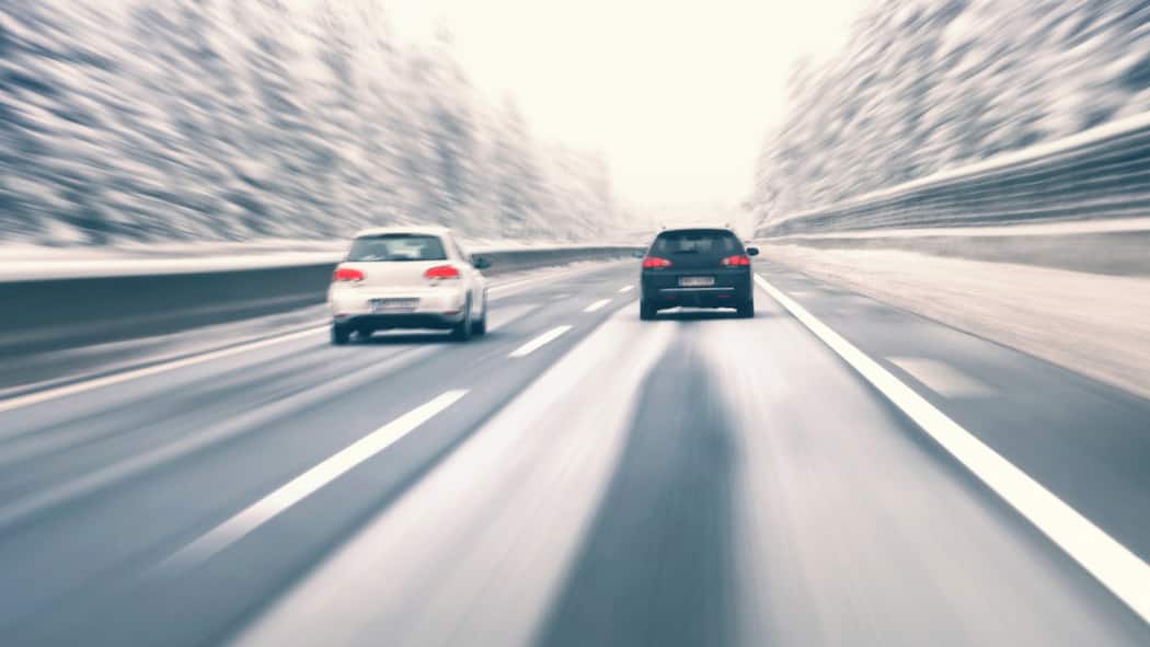 Das Fahrtempo den Umständen anpassen Zwei Autos fahren auf Autobahn im Winter