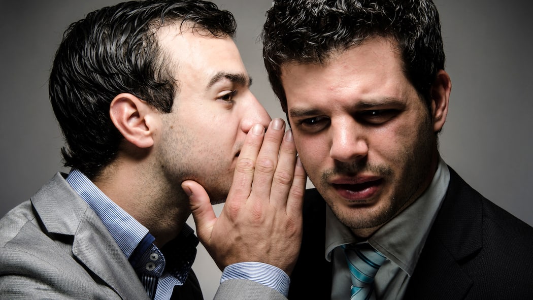 So halten Sie Ihr Risiko klein Ein Mann flüstert einem anderen Mann etwas ins Ohr