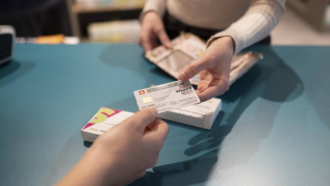 Wie einzelne Kantone jetzt die Prämienzahler entlasten wollen Frau gibt einer anderen Frau die Krankenkassenkarte - Wer profitiert von höheren Steuerabzügen für Krankenkassenprämien? Der Mittelstand oder Gutverdienende? In mehreren Kantonen laufen Initiativen. Ein Überblick