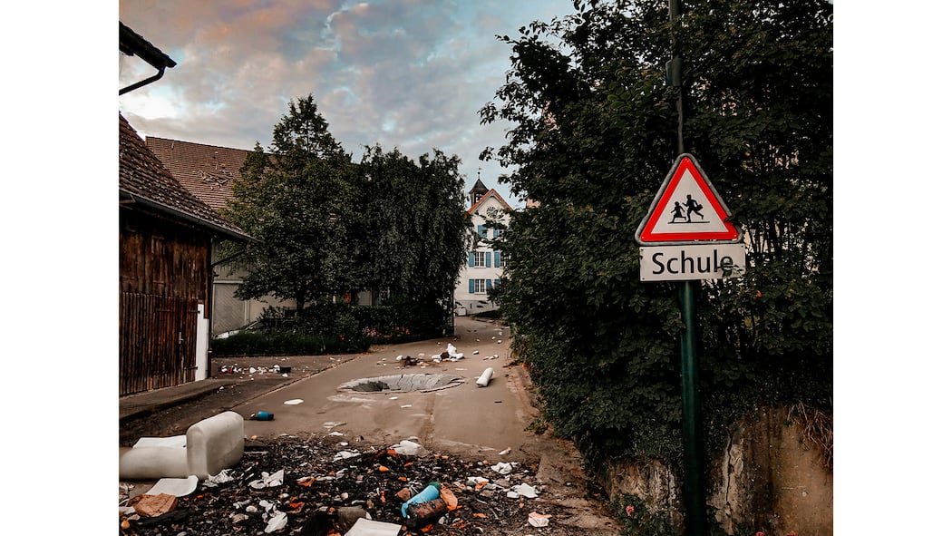 Künstler Maksym Kolisnichenko zeigt eine kriegsversehrte Schweiz Schulzone in der Schweiz mit Schutt im Vordergrund und Explosion im Hintergrund. Maksym Kolisnichenko zeigt eine kriegsversehrte Schweiz in seinem Kunstprojekt.