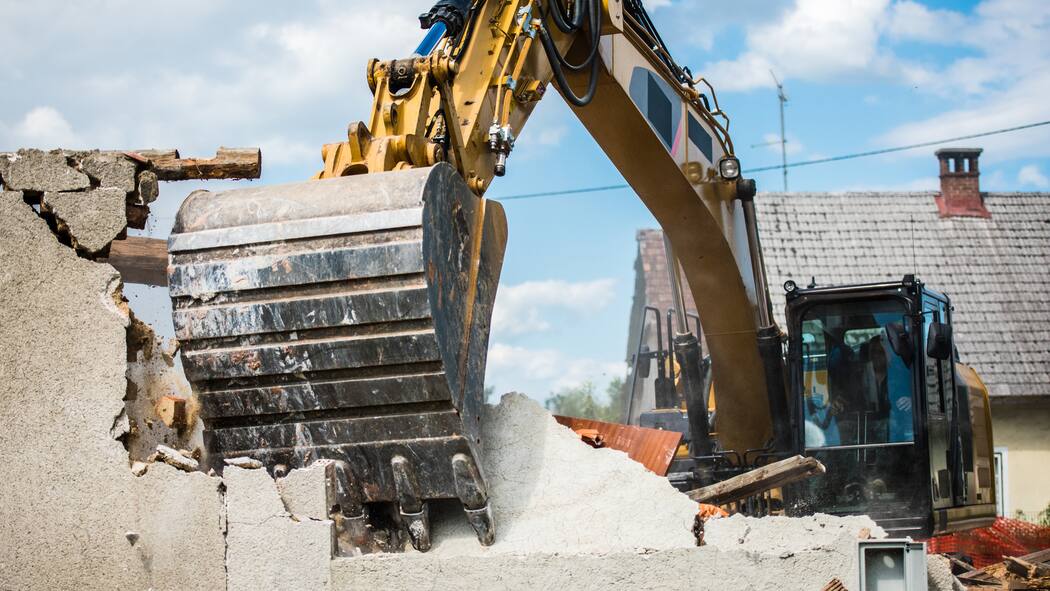 Wenn der Lärm zu viel wird Bagger zerstört eine Hausmauer