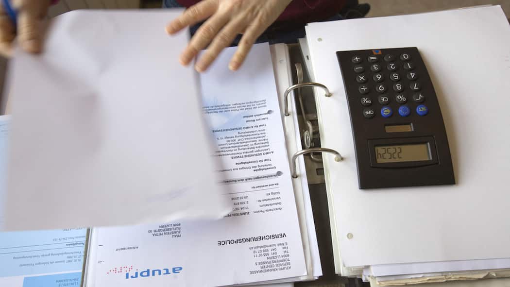 Was Sie über die Prämienverbilligung wissen müssen Eine junge Frau bei der Berechnung ihrer Krankenversicherungskosten.