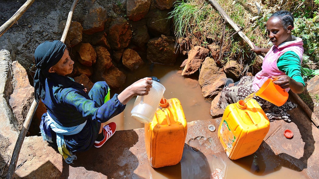Bundeshilfe für Nestlés Geschäfte Afrikanische Frauen mit Kanistern an Wasserstelle