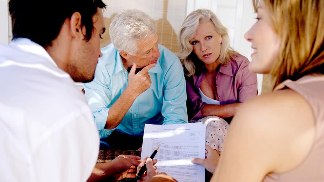 Schenken ja – aber richtig Ein älteres Paar bespricht sich mit ihren beiden erwachsenen Kindern zu Dokumenten. Dabei geht es um eine erbrechtliche Schenkung respektive um einen Erbvorbezug.