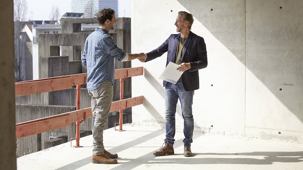 Gute Nachrichten für neue Eigentümerinnen: Längere Fristen Zwei Männer stehen auf einem Balkon eines Neubaus und schütteln sich die Hände. Die geltende gesetzliche Regelung liess nach einem Neubau von Wohnungen und Häusern nur wenig Zeit für eine Mängelrüge. Dies wird sich nun mit dem Entscheid des Schweizer Parlaments ändern.