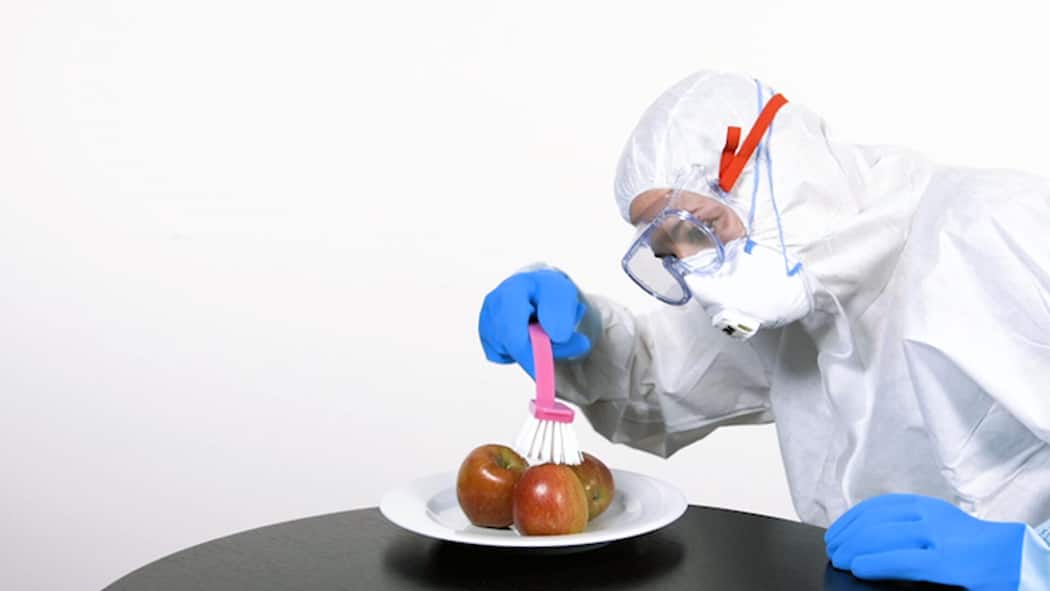 Muss man Früchte und Gemüse waschen? Dr. Claudia Twerenbold im Schutzanzug bürstet Äpfel ab.