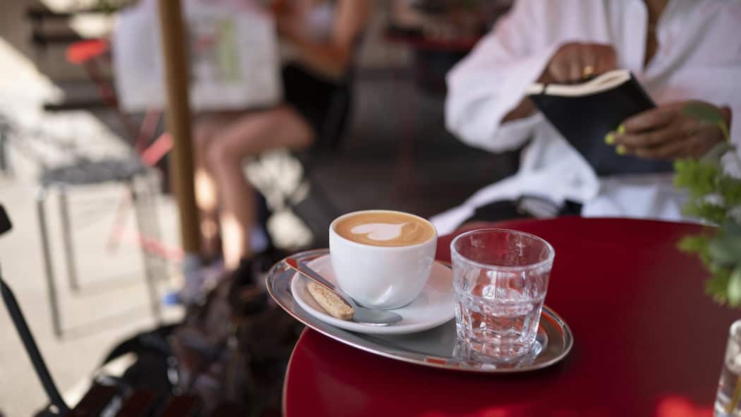 Happiger Aufpreis für Cappuccino mit Haferdrink Ein Cappuccino, zubereitet mit Haferdrink, steht auf einem Tisch eines Cafés.