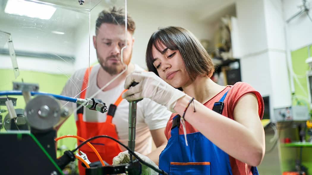 Diese Neuerungen für Junge braucht es nicht Young male mechanic and teenage female mechanic working with tools in the storage room of an auto repair shop, side view