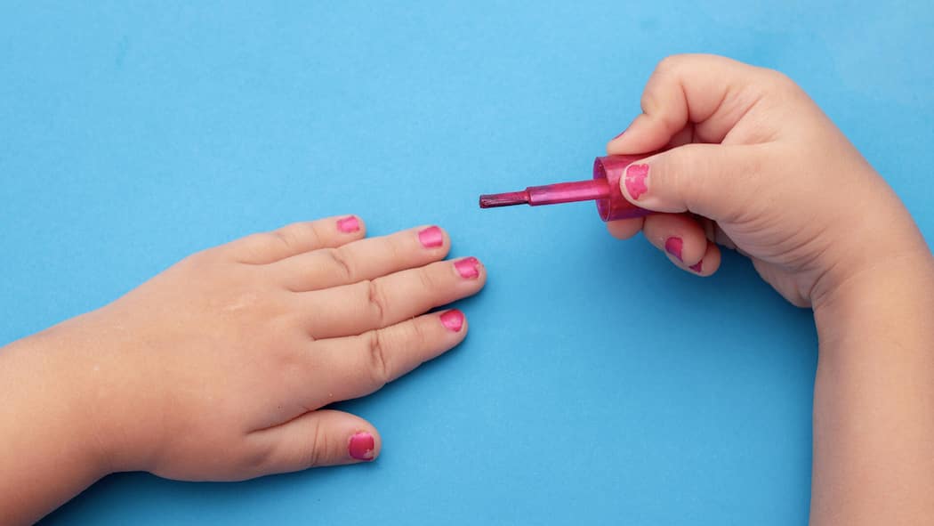 Gefährliche Stoffe in Nagellack und Lippenpomade für Kinder 2AH2E5D children's manicure. Children's hands paint their nails with Colorful nail polish. Red manicure on childish nails.
