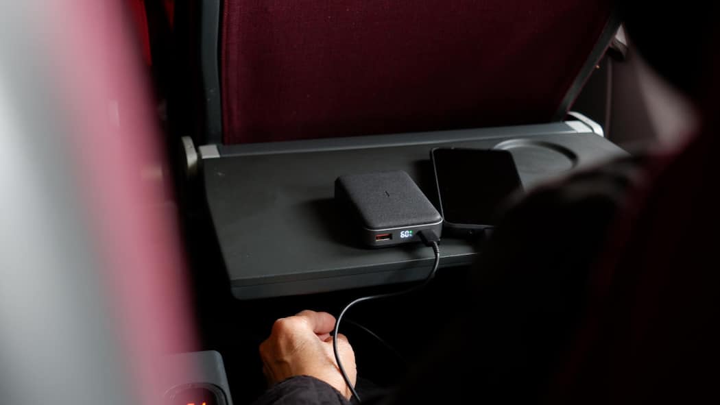 Diese Regeln gelten für Powerbanks im Flugzeug Ein Fluggast lädt in einem Flugzeug sein Smartphone mithilfe einer Powerbank auf.