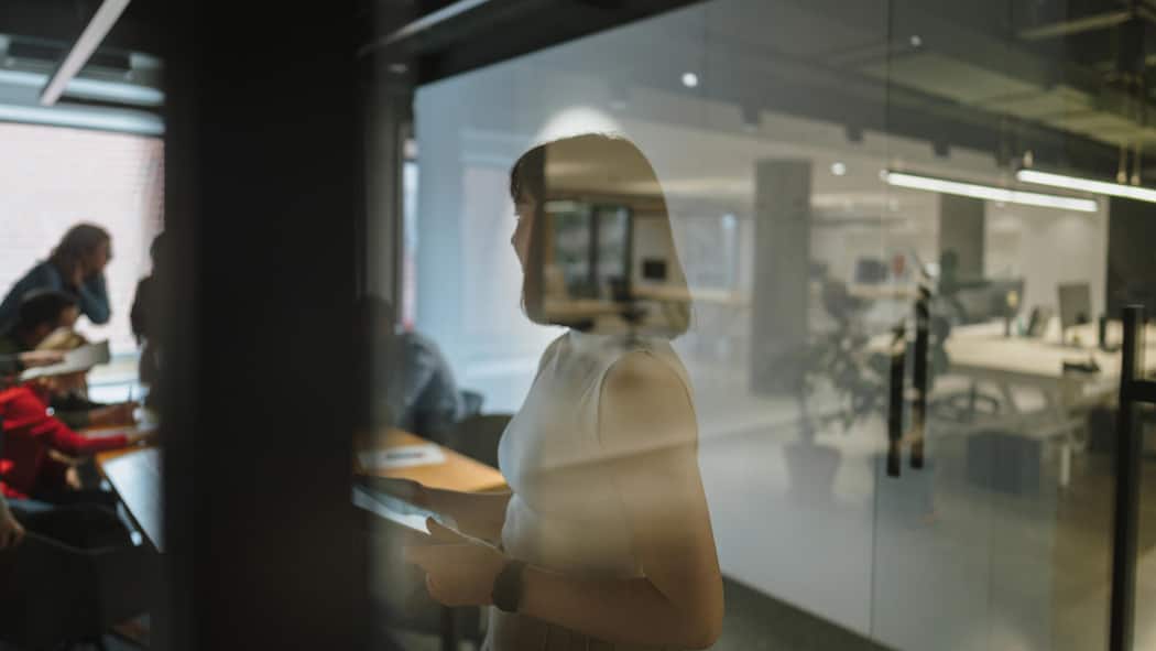 Der Rachefeldzug einer Firma gegen eine Angestellte Photo of a young woman using a tablet in her office, preparing for a meeting, and reviewing meeting notes as she is about to start a professional discussion with her coworkers.