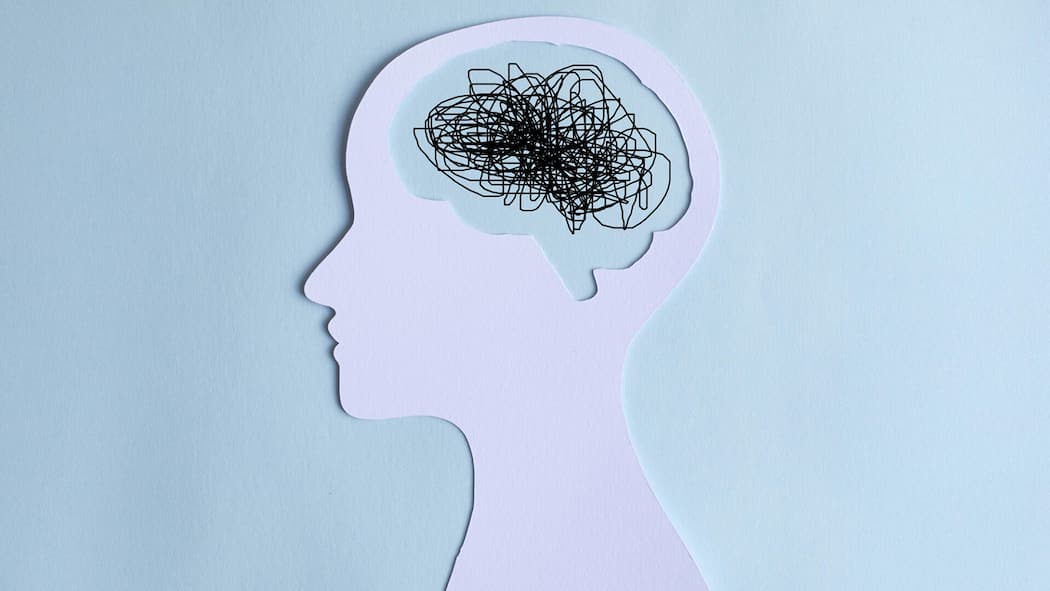 Stiftung zahlt Therapie für Traumaopfer Paper cut out of a human head with a chaotic line drawing for a brain. Burn out or mental overload Concept