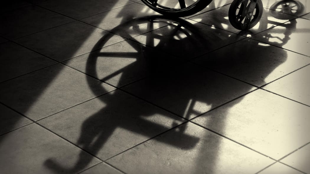 Stiftung zahlt Stehhilfe für einen Paraplegiker Shadow of a wheelchair, showing part of the wheelchair at the top of the image.