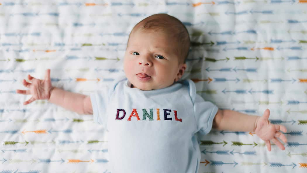 Wir müssen über Dani reden Baby im Strampler mit Namen Daniel aufgestickt.