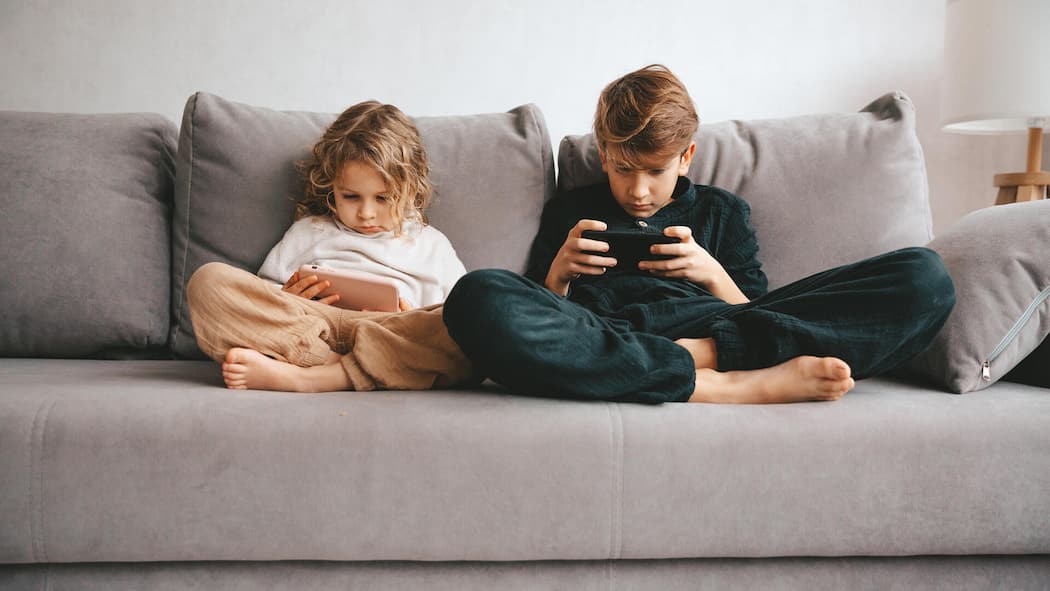 Darum macht der Bildschirm Kinder zu Hektikern und Träumerinnen Beautiful little girl and teenager boy with smartphone. Leisure, children, technology and people concept