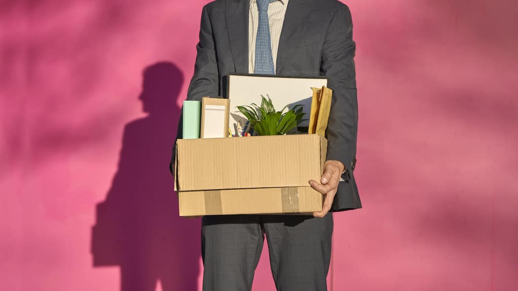 Mündlich gekündigt – ist das überhaupt gültig? Ein Mann im Anzug hält einen Karton mit Büromaterial. Wann eine mündliche Kündigung gültig ist.