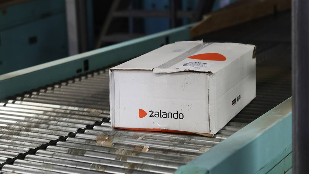 Zweifelhafte Labels bei Zalando und About You Paket von Zalando liegt auf Förderband