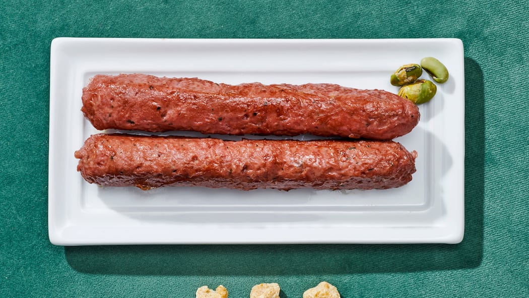 Ab fünf Zutaten wirds kritisch Zwei Cevapcici auf einem Teller auf grünem Untergrund. Warum ultrahochverarbeitete Lebensmittel ungesund sind