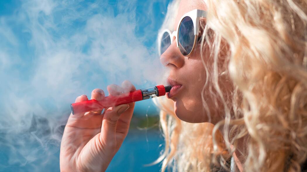 Stoff in E-Zigaretten ist krebserregend Frau zieht an E-Zigarette