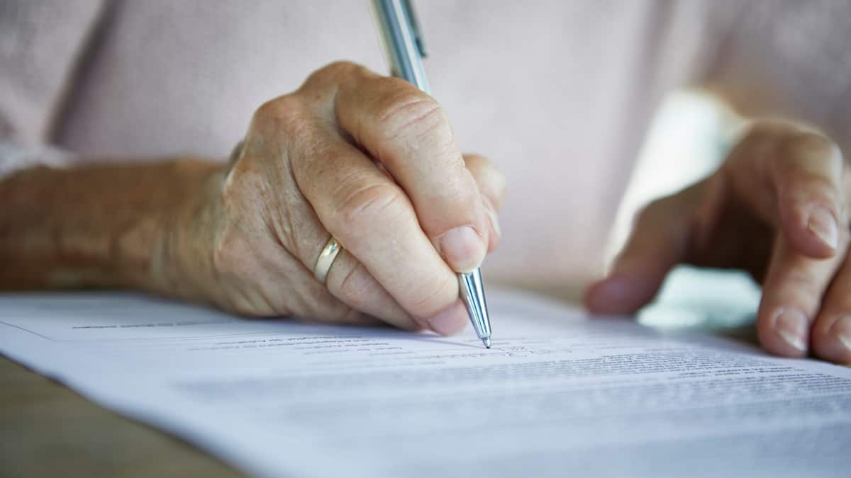 Hände von Seniorin unterschreiben ein Dokument