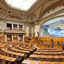 Haben Sie bei den Wahlen den Durchblick? Leere Stühle und Bänke im Nationalratssaal im Bundeshaus in Bern. Im Herbst 2023 stehen eidgenössische Wahlen des Parlaments an. Erfahren Sie im Quiz, was Sie dazu wissen müssen und verbessern Sie Ihren politischen Horizont.