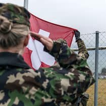 Frauen sollen auch einen Dienst leisten Eine Frau im Militär mit Schweizer Flagge.