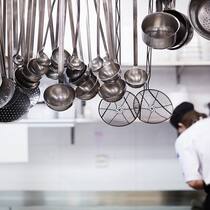 Gewerkschaft widerspricht dem Hotelierpräsidenten Junge Person bei der Arbeit in der Industrieküche. Schöpfkellen hängen von der Decke.
