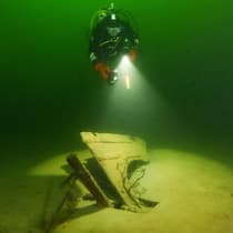 Das gilt, wenn Sie sich auf Schatzsuche begeben Taucher beleuchtet ein versunkenes Schiffsteil im Zürichsee