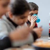 «Ekel und Furcht» – Organisationen kritisieren Schweiz Junge trinkt aus Plastikbecher und sitzt mit seiner Familie am Esstisch in der Asylunterkunft. Ein Drittel aller Asylgesuche in der Schweiz kommt von Kindern