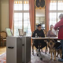 9 Fakten zur Schweizer Demokratie Eine ältere Wählerin gibt in einem historischen Saal ihre Stimme an der Urne ab.