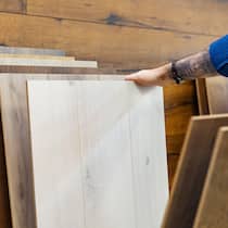 Woher kommt das Holz? Viele Firmen schummeln Auf dem Bild sind Holzplatten an einer Wand angelehnt, jemand wählt mit den Händen daraus aus.