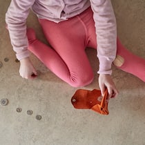Die Sozialhilfe für Kinder reicht nicht aus Ein Mädchen in pinken Strumpfhosen sitzt auf dem Boden, in den Händen ein fast leeres Portemonnaie. Auf dem Boden vor ihr hat sie einige Geldmünzen ausgebreitet.