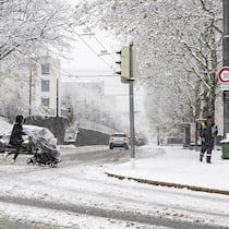 Zu spät im Büro – muss ich länger arbeiten? Eine Person überquert mit einem Kinderwagen die verschneite Strasse in Lausanne. Müssen Arbeitnehmerinnen und Arbeitnehmer länger arbeiten, wenn sie wegen des Schnees und vereister Strassen zu spät zur Arbeit kommen?