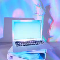 Aktenberge an den Gerichten sind bald passé Ein Laptop auf gestapelten Aktenordnern, im Hintergrund ist als Schatten die Justizia zu sehen