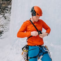 Sind Lawinensuchgeräte fehleranfällig? Banff, Alberta, Canada - March 07, 2022: A male ice climber puts on his avalanche transceiver while standing at the base of a climbing route on Mount Rundle in Banff National Park on March 07, 2022. Ice climbing routes in the Canadian Rockies are often heavily threatened by avalanche terrain.