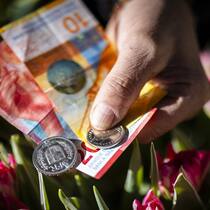 Wie der Franken jetzt in die Verfassung kommen soll Ein Blumenhaendler zeigt Schweizer Franken in Noten und Muenzen am Wochenmarkt auf dem Buerkliplatz, am Dienstag, 13. Februar 2024 in Zuerich. Der Schweizer Franken hat nach der Bekanntgabe ueberraschend tiefer Inflationsdaten gegenueber dem US-Dolla…