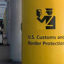 10 Tipps für USA-Reisende U.S. Customs And Border Protection Symbol U.S. Customs and Border Protection CBP sign, inscription and symbol in yellow background in Newark Liberty International Airport EWR serving the New York Metropolitan area with arriving passenger walking in t…
