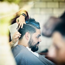 Preisschock im Coiffeurstuhl? Ist nicht erlaubt! Ein Mann beim Coiffeur aus der Profilansicht. Wie Coiffeurpreise zustandekommen.