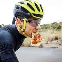 So ernähren sich Hobbysportler richtig Ein Velofahrer mit Helm und Brille hat ein Stück Pizza im Mund. Die wichtigsten Fragen zu Ernährung und Sport.