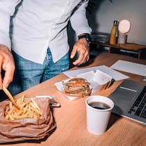Ist schon wieder Schluss mit Homeoffice? Männerhand mit Pommes im Homeoffice vor dem Computer