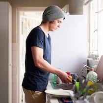Was tun, wenn die Wohnung teurer ist als der Staat bezahlt? Junger Mann in der Küche - Wer Sozialhilfe bekommt, darf keine hohen Mietkosten haben. Das ist vielerorts eine Herausforderung für Betroffene