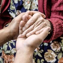 Streit um Geld für pflegende Angehörige Eine Pflegerin hält die Hand einer Seniorin.