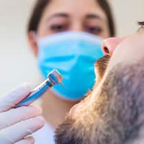 Zahnarztkosten sparen – so gehts Eine Zahnärztin setzt bei einem Patienten zum Bohren an.