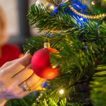 Dank Spenden ein wichtiges Weihnachtsgeschenk Frau hängt Christbaumkugel an Christbaum