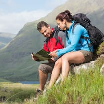 Vorbereitung und Tipps für Neuwanderer Zwei Wanderer sitzen auf einem kleinen Felsvorstoss und schauen sich zusammen eine Karte an.