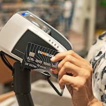 Ist die Limite der Karte wählbar? Eine Frau bezahlt im Supermarkt mit der Kreditkarte kontaktlos.